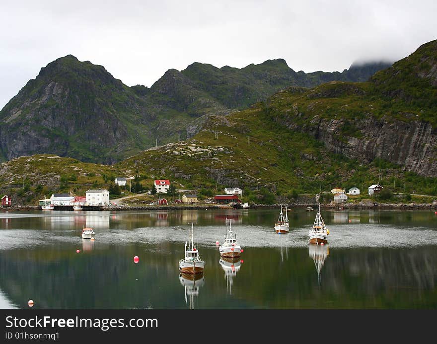 A small fishing port in the lofoten islands with boats reflected in the sea, Norway. A small fishing port in the lofoten islands with boats reflected in the sea, Norway