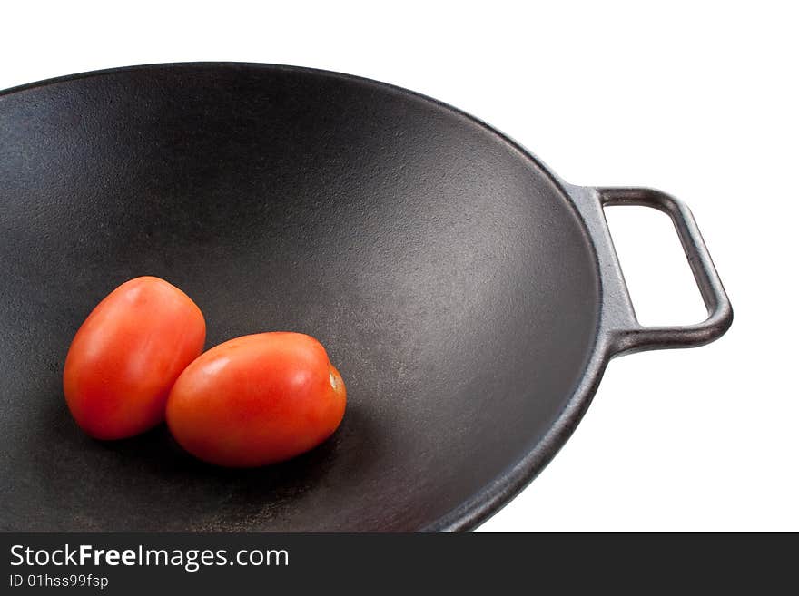 Two roma tomatoes in a black cast iron wok. Two roma tomatoes in a black cast iron wok