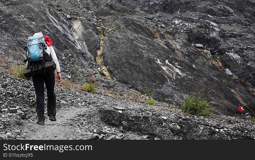 Girl with backpack high trekking along the rocky mountain