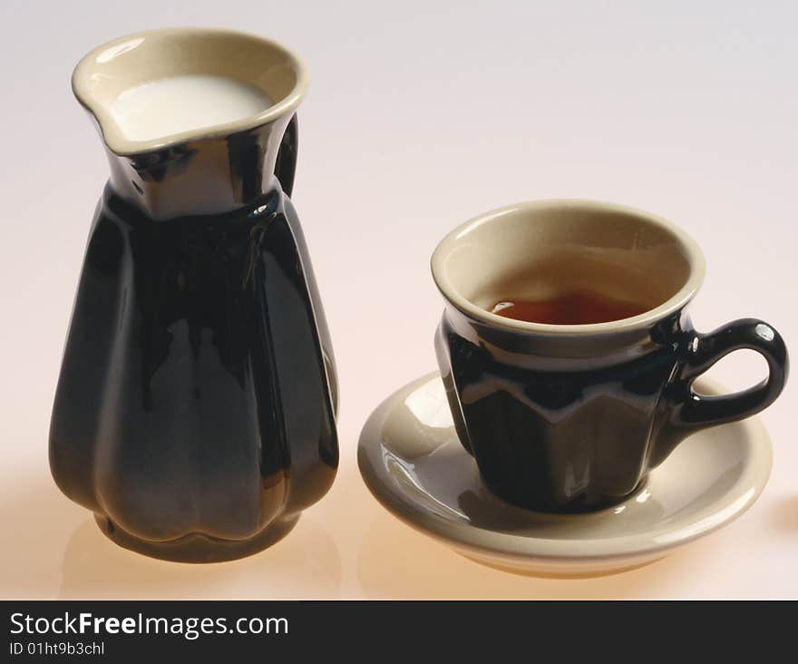 Tea and milk in black cups isolated on a white background