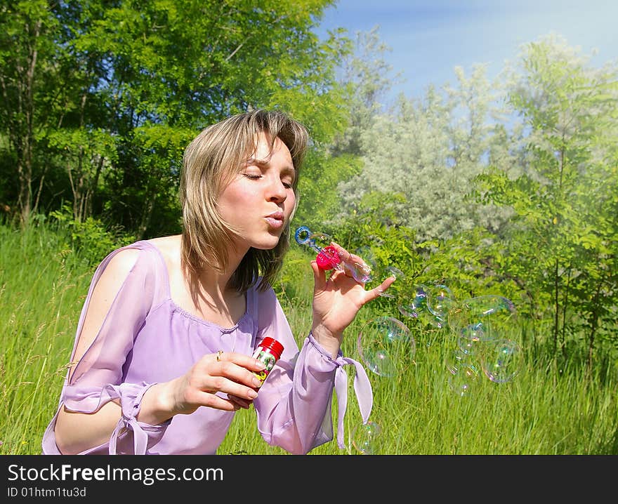 Cute young woman blows a soap bubbles