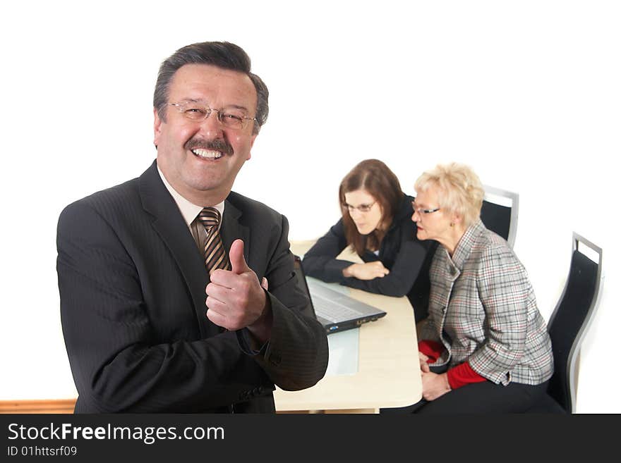 Businessman showing tumb up sign in office environment. Three people with focus on mature man in front. Isolated over white. Businessman showing tumb up sign in office environment. Three people with focus on mature man in front. Isolated over white.