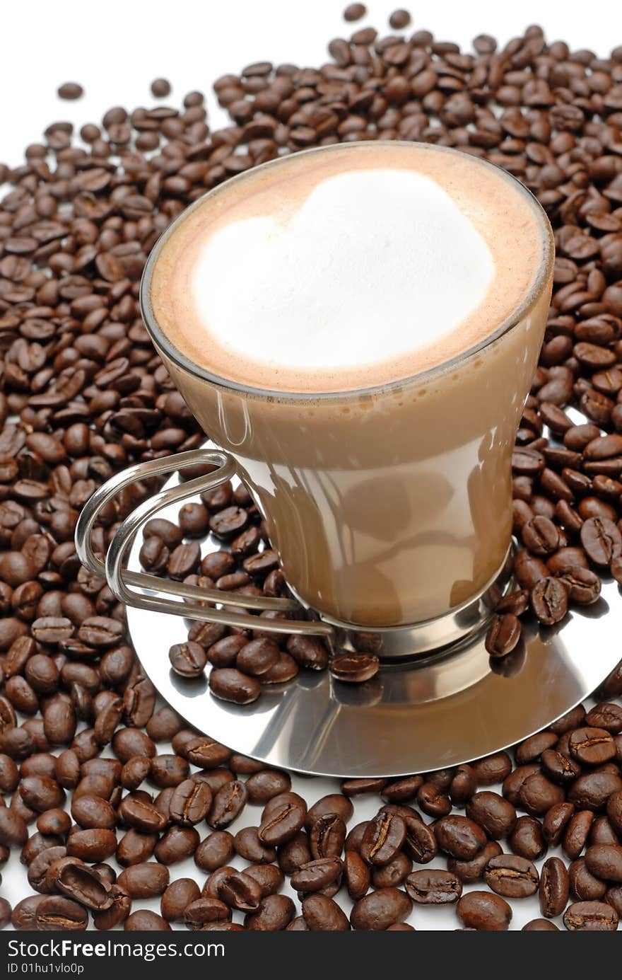 A cup of cappuccino and roasted coffee beans