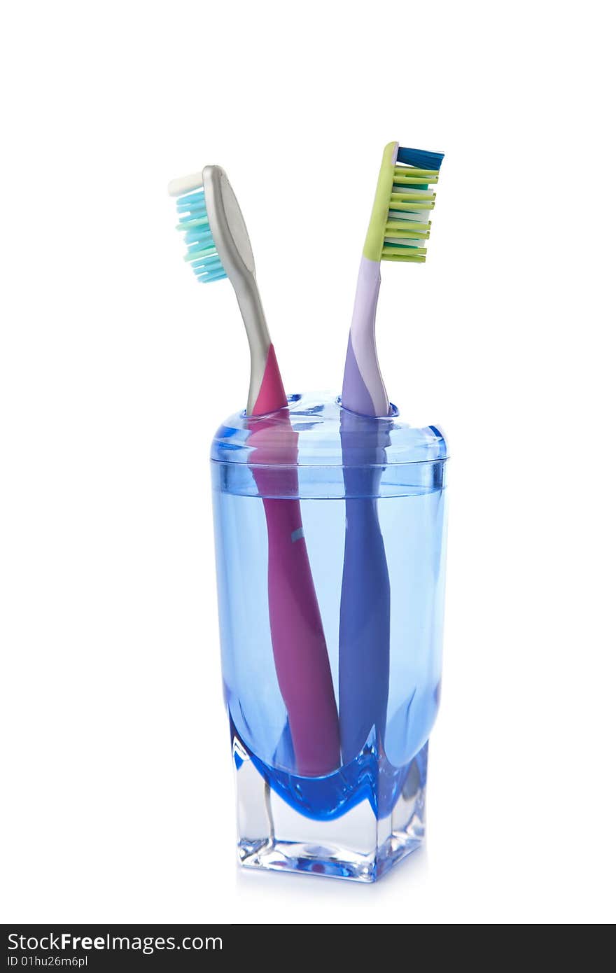 Two Colorful Toothbrushes In Glass Isolated