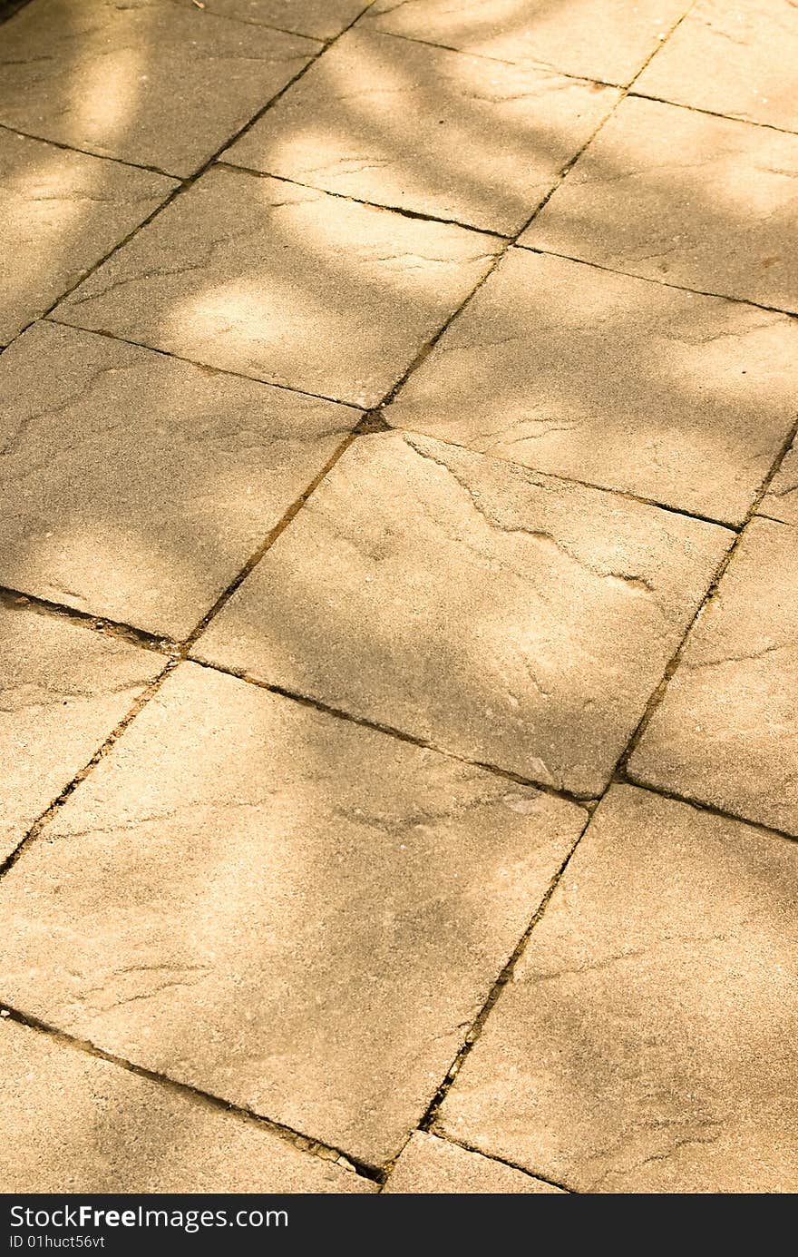 Dappled light on stone texture of path or sidewalk as background for spring or summer