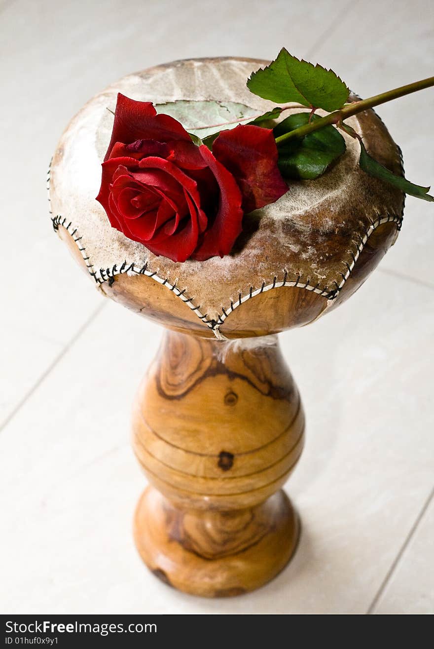 A red rose laying on a Indian drum instrument. A red rose laying on a Indian drum instrument