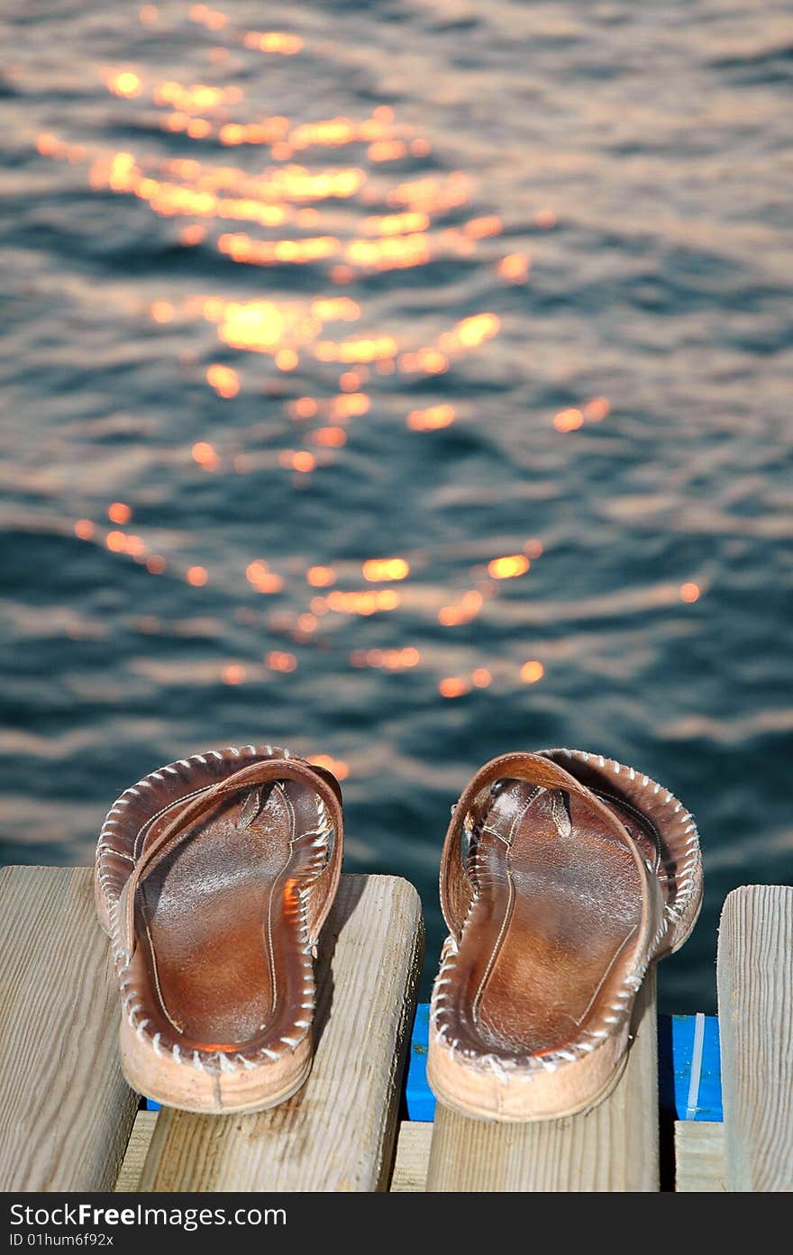 Leather sandals standing on water edge in sunset light. Leather sandals standing on water edge in sunset light