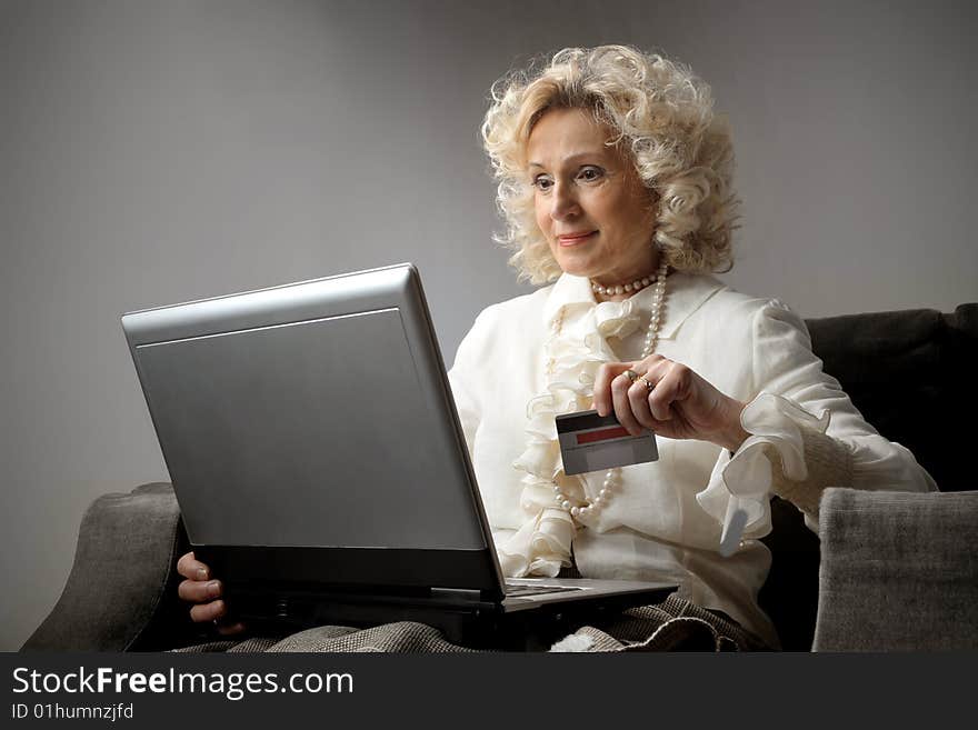 A senior woman with credit card using a laptop. A senior woman with credit card using a laptop