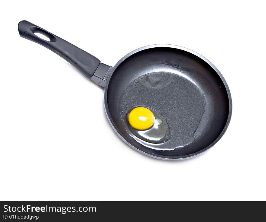 A raw egg in a frying pan on white background. A raw egg in a frying pan on white background.