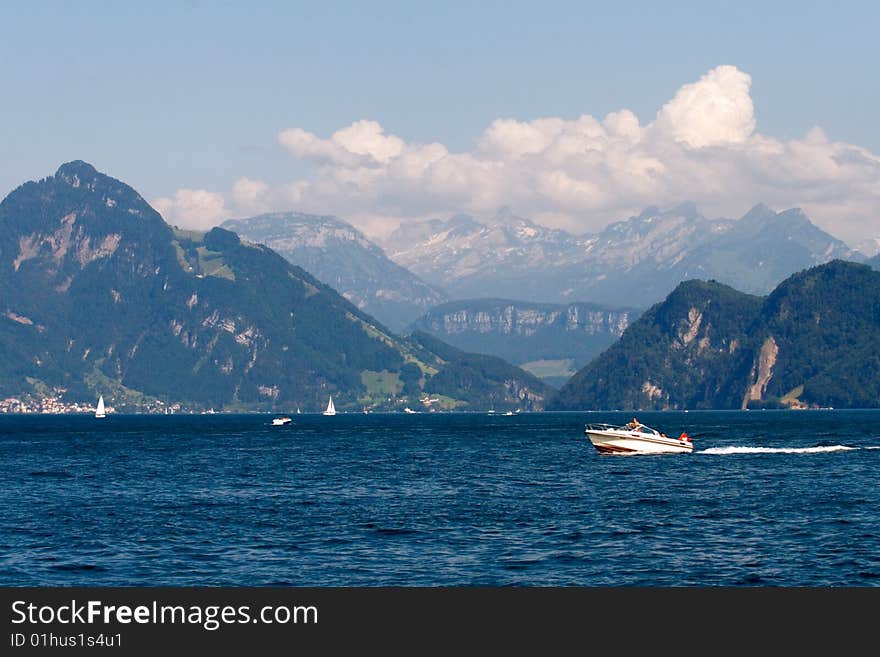 Landscape with lake, sailboats and mountains