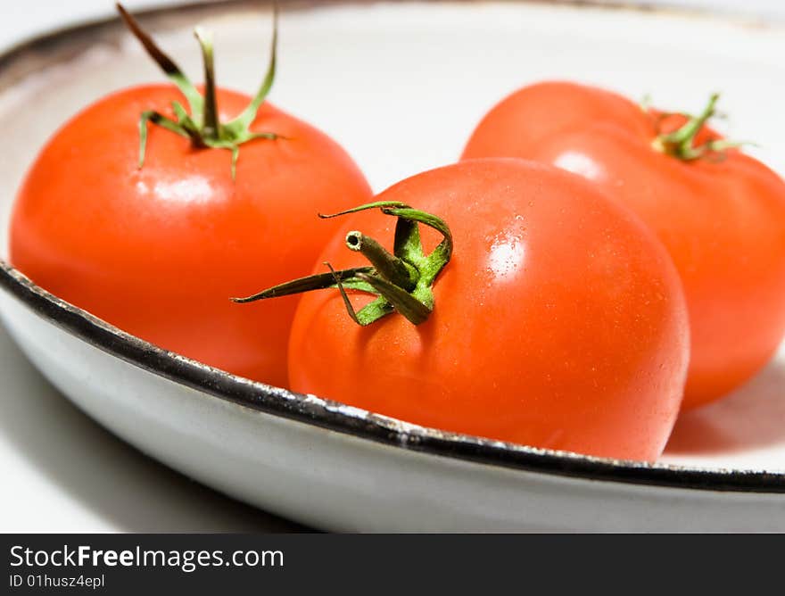 Three tomatoes in a old white plate. Three tomatoes in a old white plate