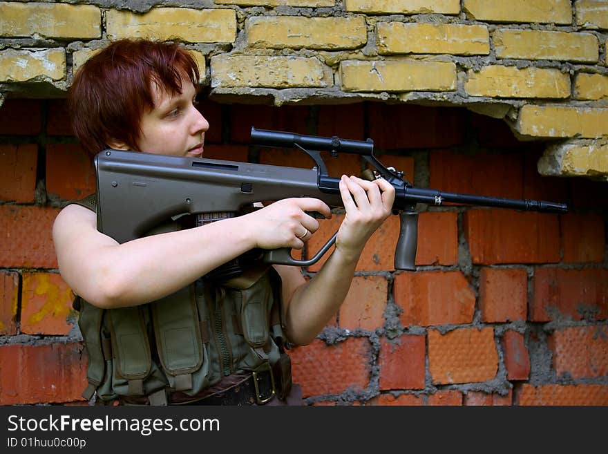 Shooting soldier with an assault rifle in front of a wall