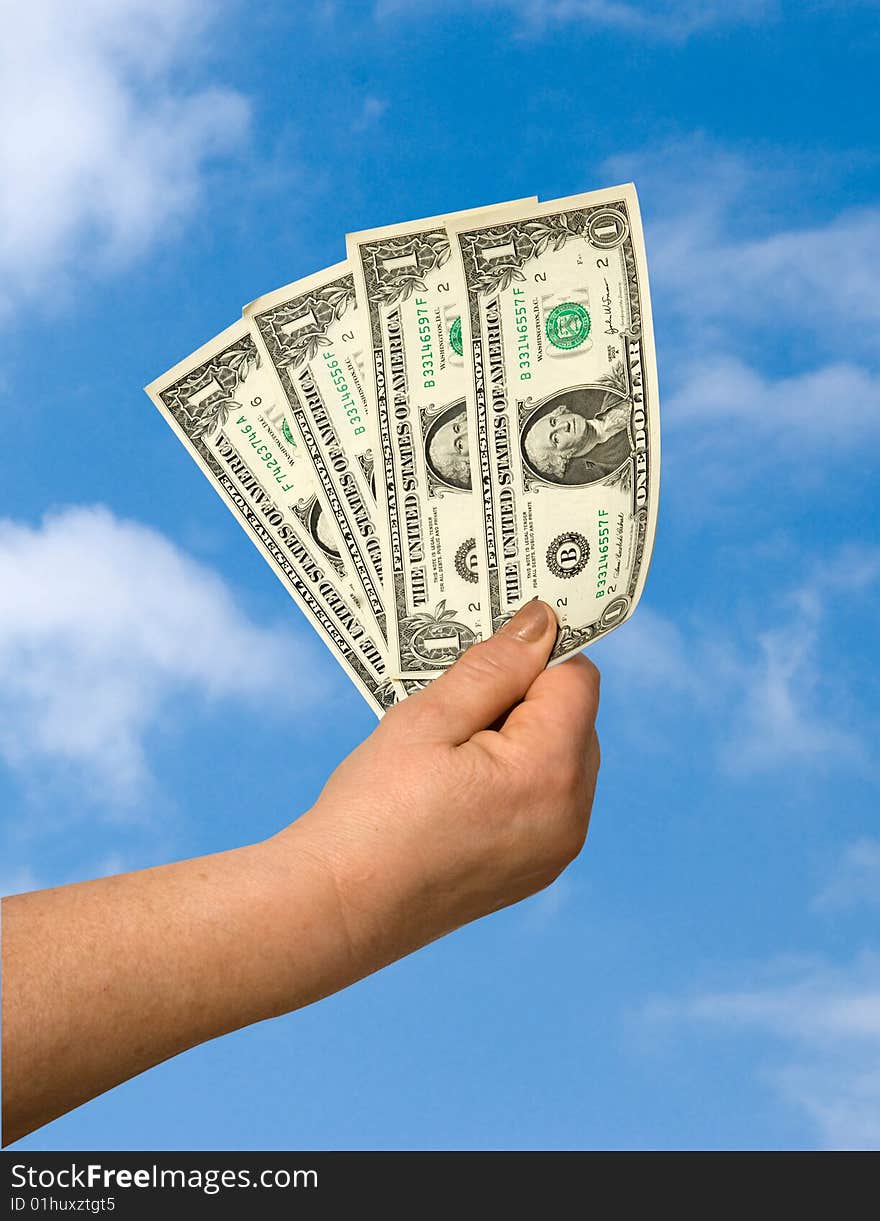 Hand with dollars on sky background