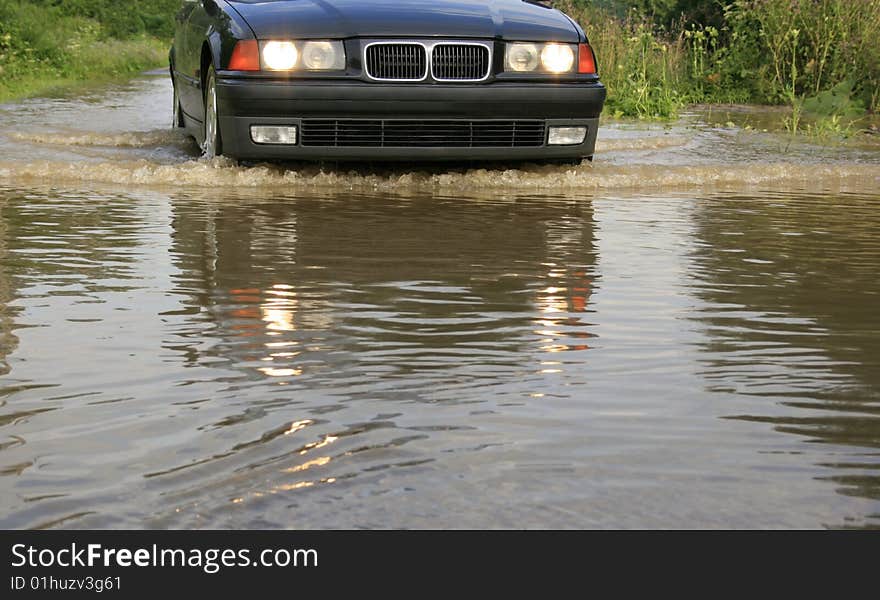 Water splashes from under the wheels, dangerous ride of the car through large water, flood, reckless driving, driving through a river overflow, water on road after downpour, obstacle course, come encounter an obstacle