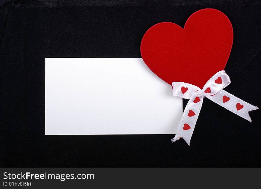 Red heart with empty card on velvet.