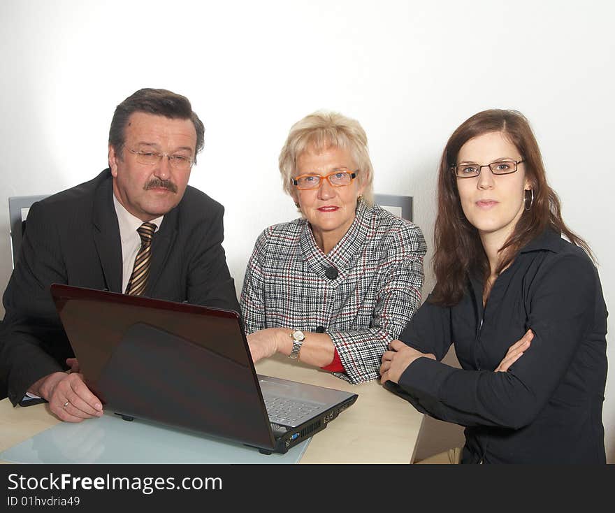 A business team of three sitting in front of a laptop. Isolated over white. A business team of three sitting in front of a laptop. Isolated over white.