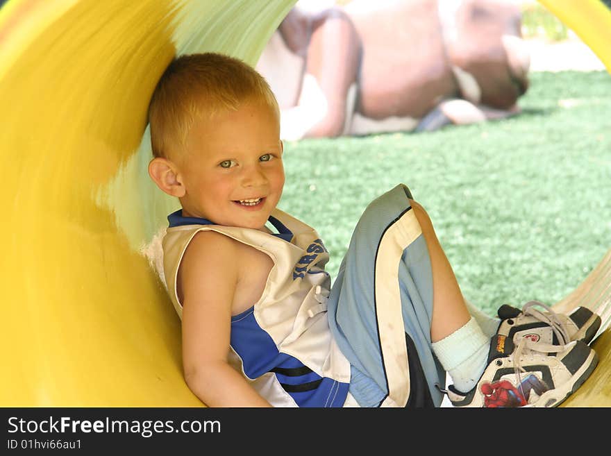 Color image of a young boy in a yellow tunnel at the park. Color image of a young boy in a yellow tunnel at the park.