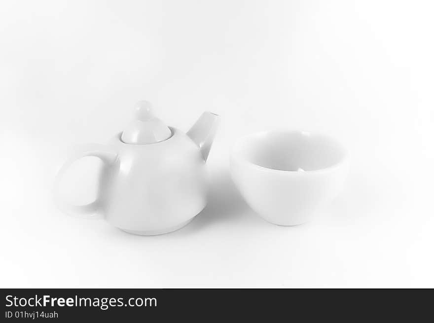 White teapot and teacup on the white light background. White teapot and teacup on the white light background