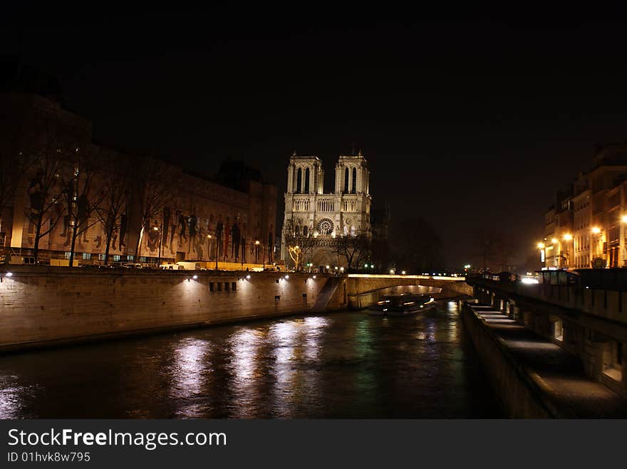 Siene river in paris at night with notre dame church in the background