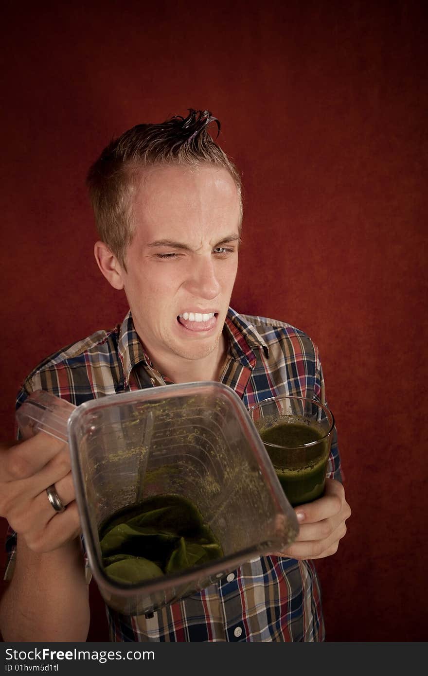 Young man grimacing and holding unappetizing blended health shake. Young man grimacing and holding unappetizing blended health shake