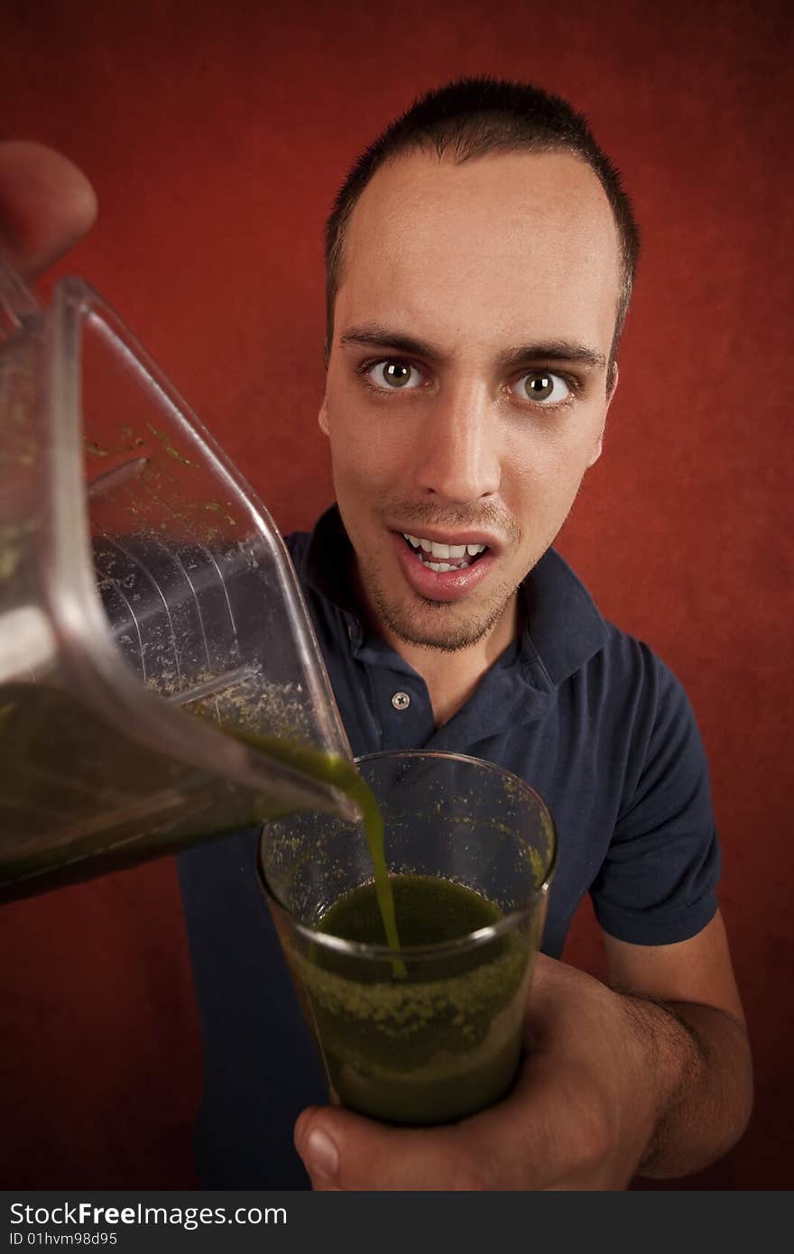 Young man holding unappetizing blended health shake. Young man holding unappetizing blended health shake