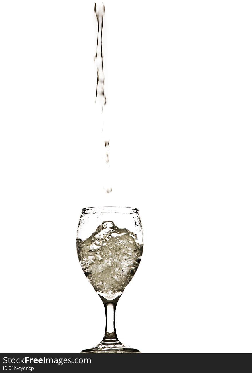 A stream of water splashing into and filling a wine glass. A stream of water splashing into and filling a wine glass.