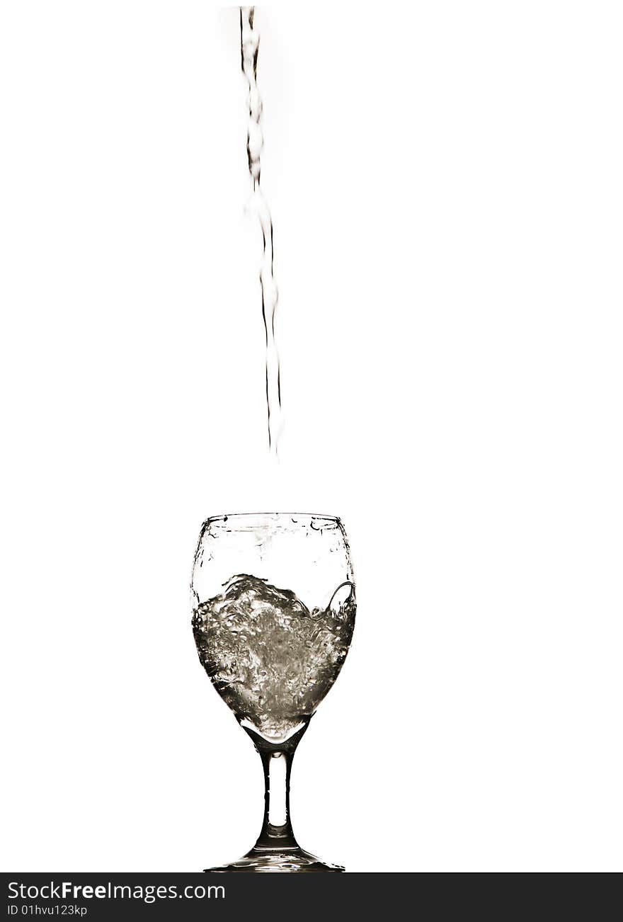 A stream of water splashing into and filling a wine glass. A stream of water splashing into and filling a wine glass.