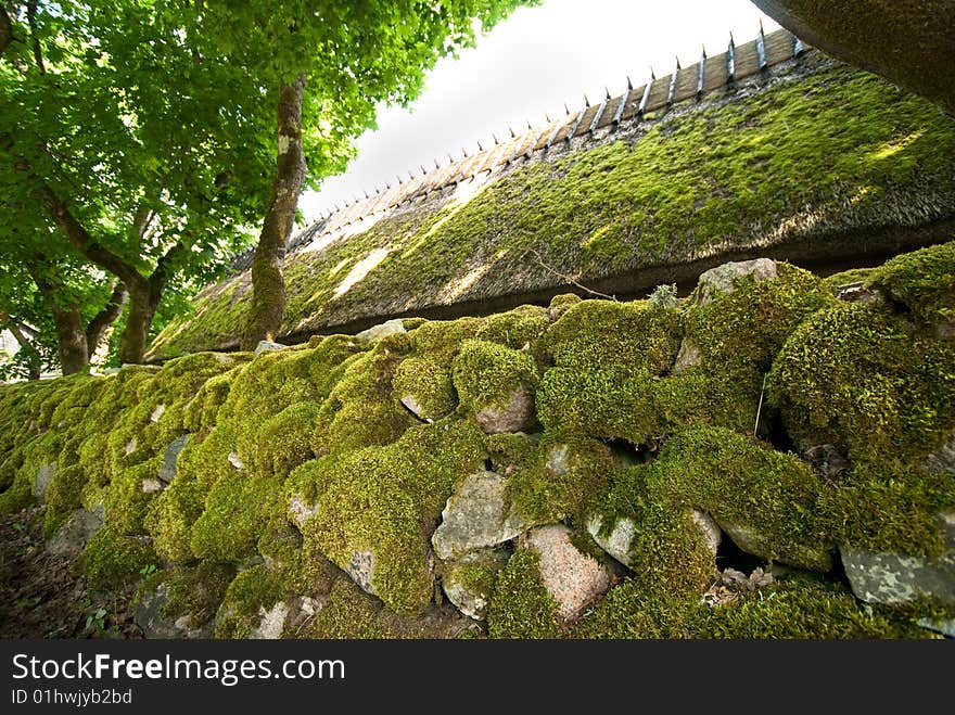 Thatched roof and rock fence is covered by moss in beautiful day. Thatched roof and rock fence is covered by moss in beautiful day