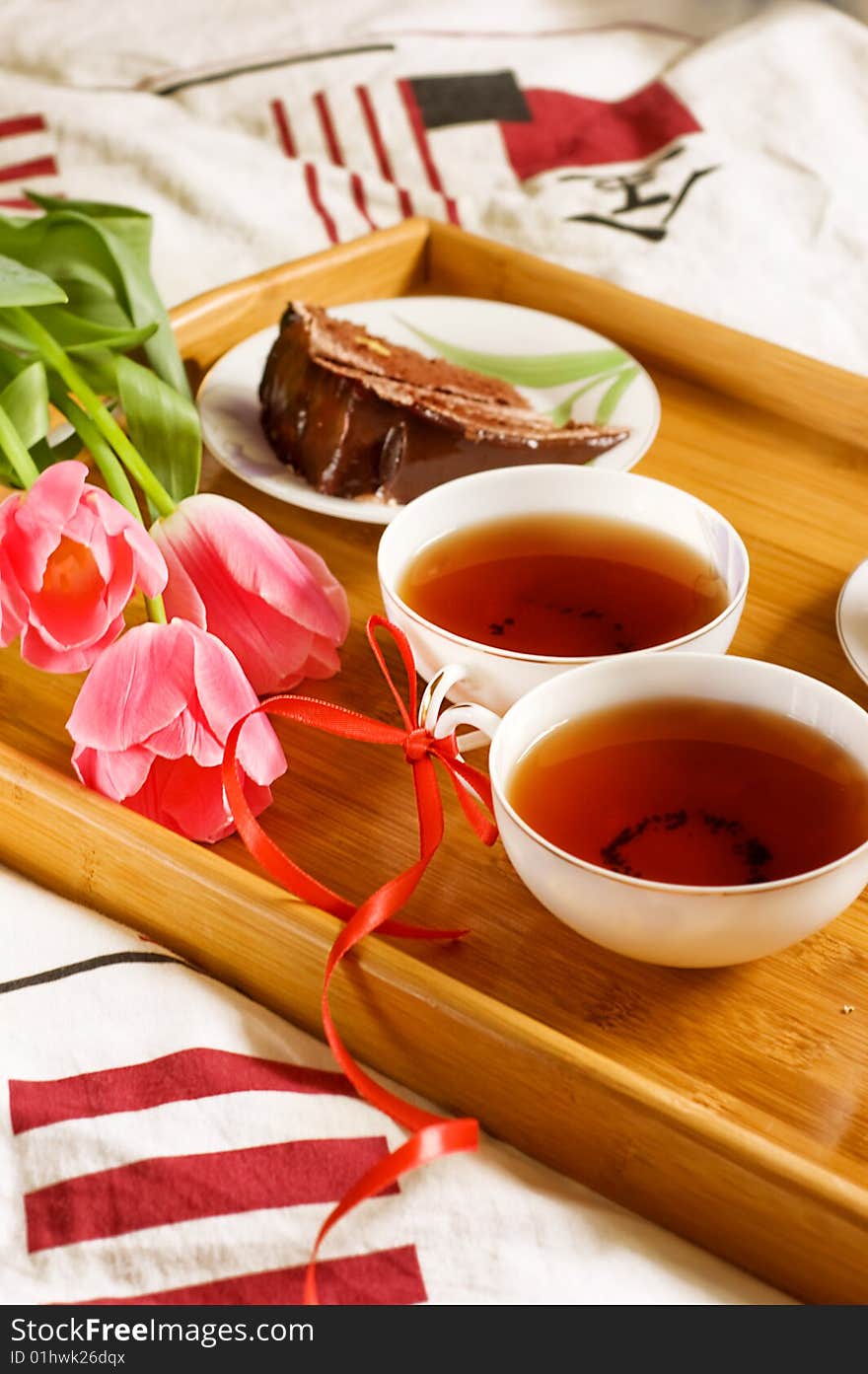 Breakfast tray on bed with tea, cakes and tulips. Breakfast tray on bed with tea, cakes and tulips