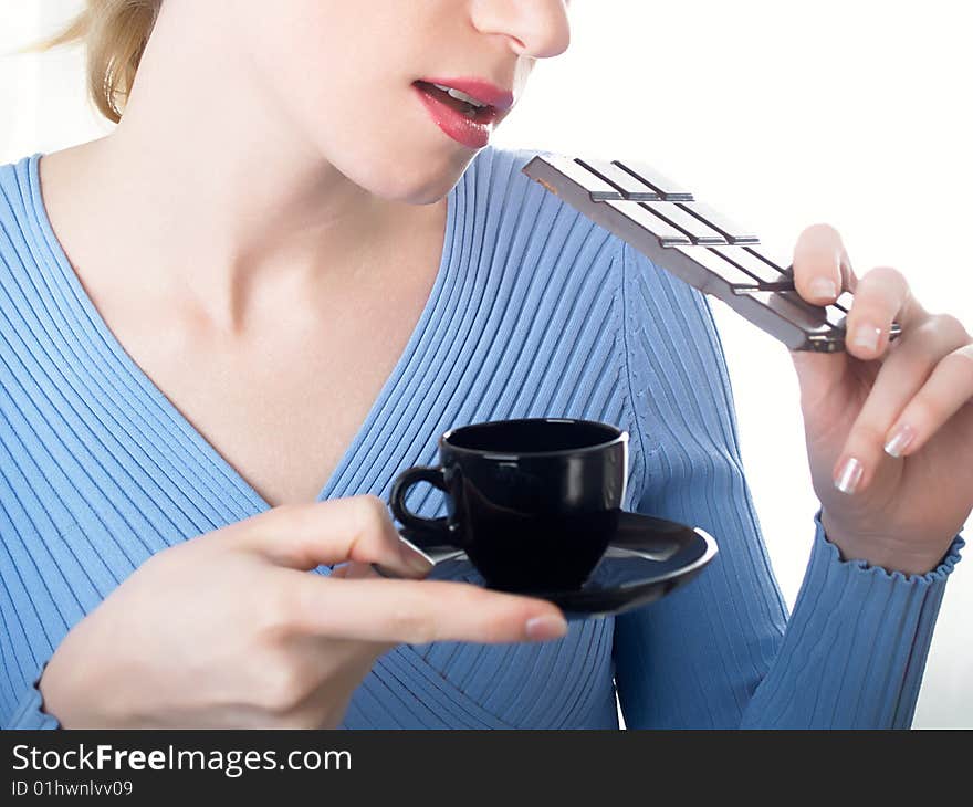 The beautiful girl with a coffee cup in a hand and chocolate