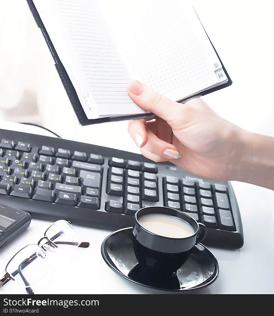 Hand whith notebook. Cup, keyboard and glass. Hand whith notebook. Cup, keyboard and glass