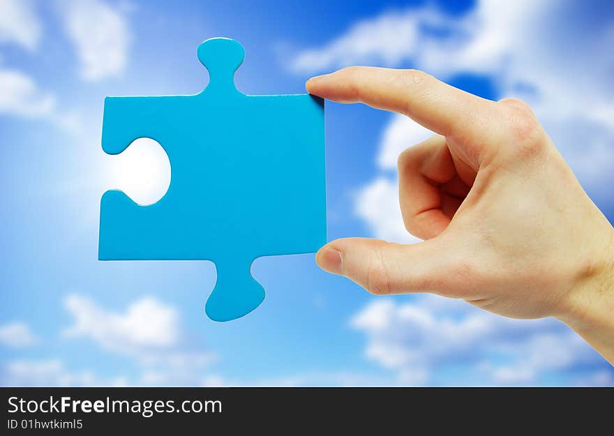 Puzzle in hand isolated on sky background