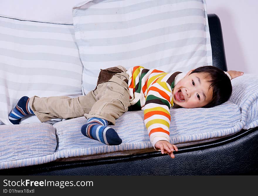 A picture of a little chinese boy playing happily on sofa at home. A picture of a little chinese boy playing happily on sofa at home