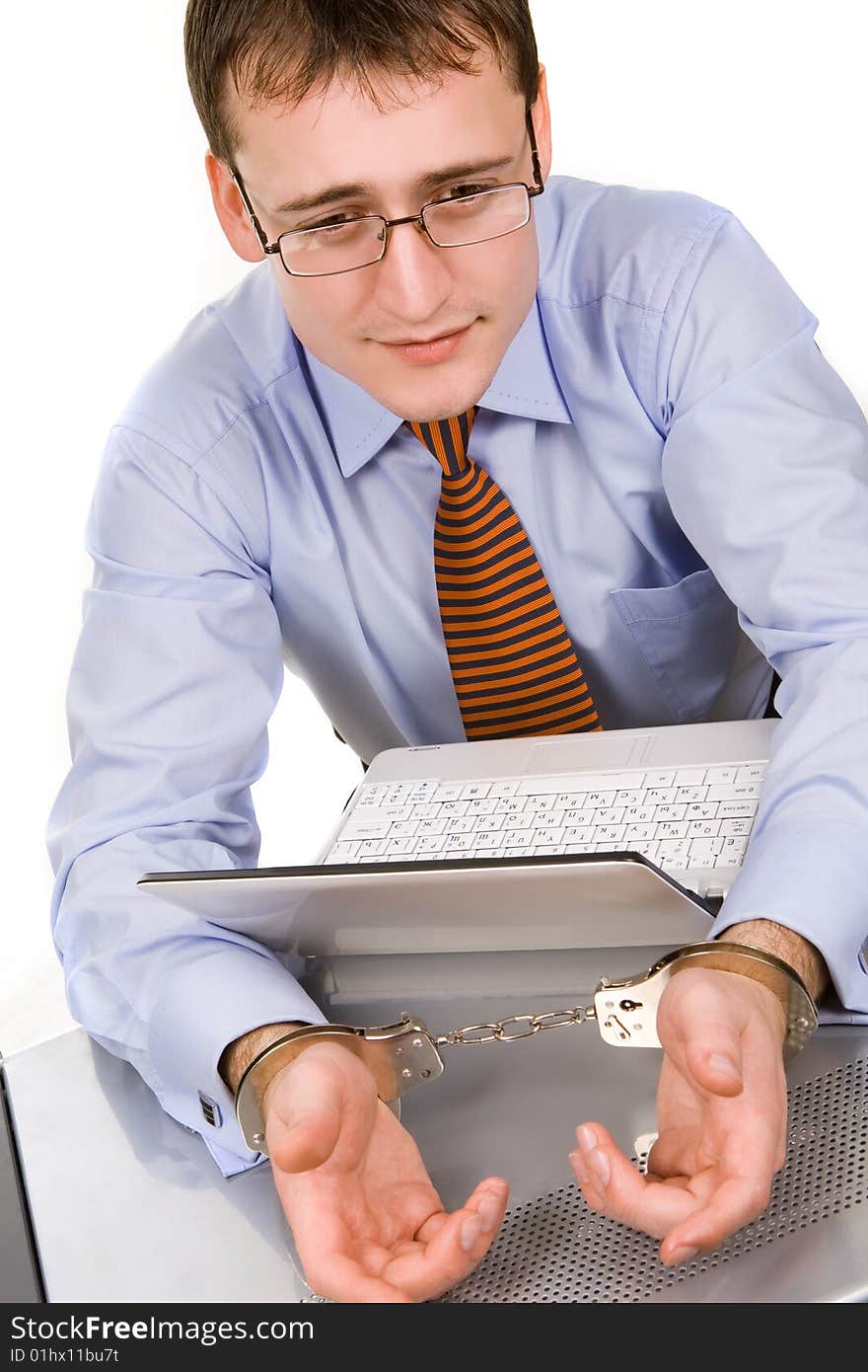 Handsome young businessman bound to laptop with handcuffs. Handsome young businessman bound to laptop with handcuffs