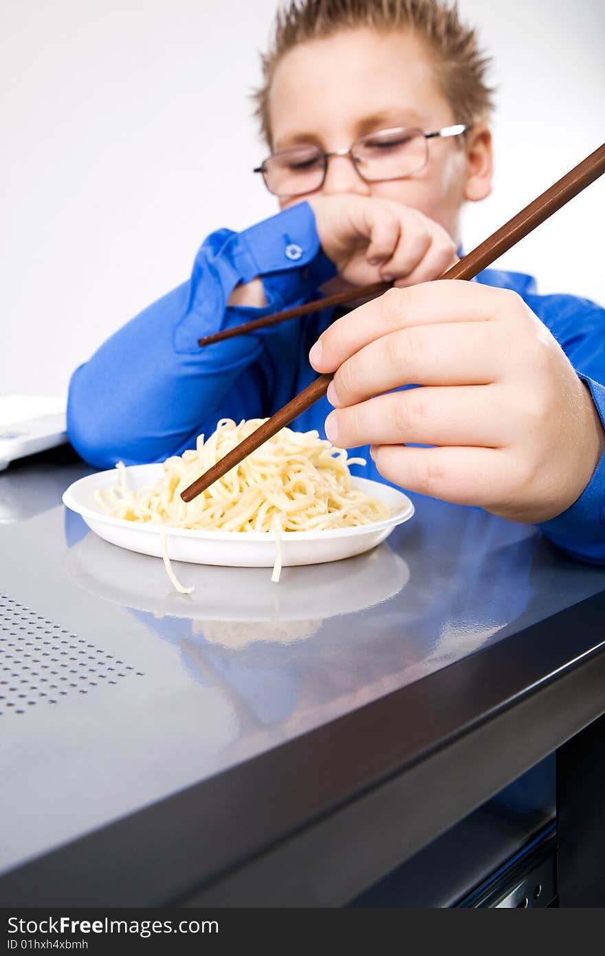 Hungry boy eating chinese noodles with sticks