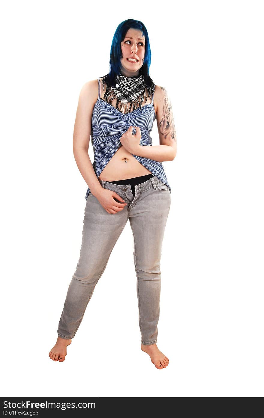 Pretty young blue haired girl in a short blue dress and jeans with a big tattoo on her arm standing on the floor and opens her jeans, for white background. Pretty young blue haired girl in a short blue dress and jeans with a big tattoo on her arm standing on the floor and opens her jeans, for white background.