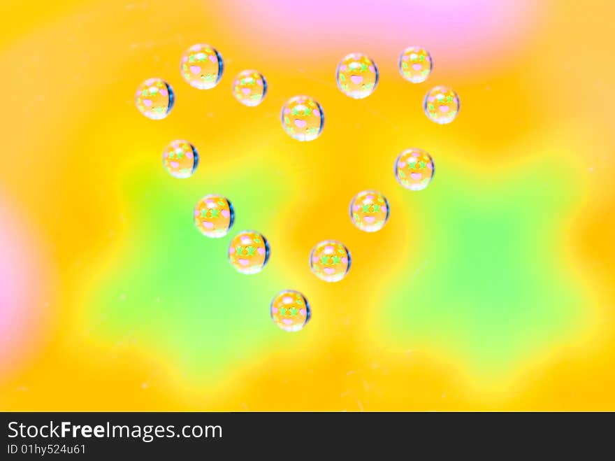 Water drops in the form of heart on a multi-coloured celebratory background