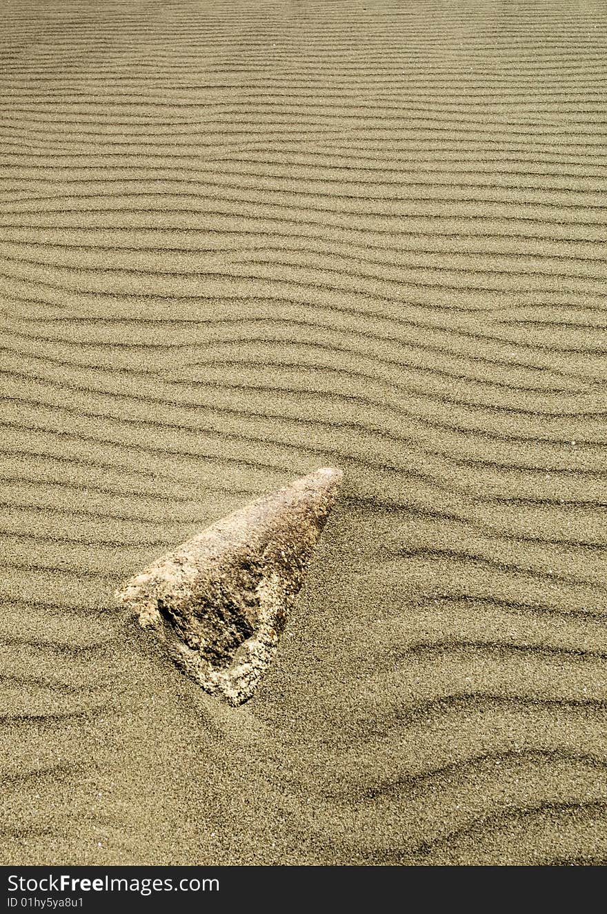 A rock is nearly buried by wind blown sand. A rock is nearly buried by wind blown sand