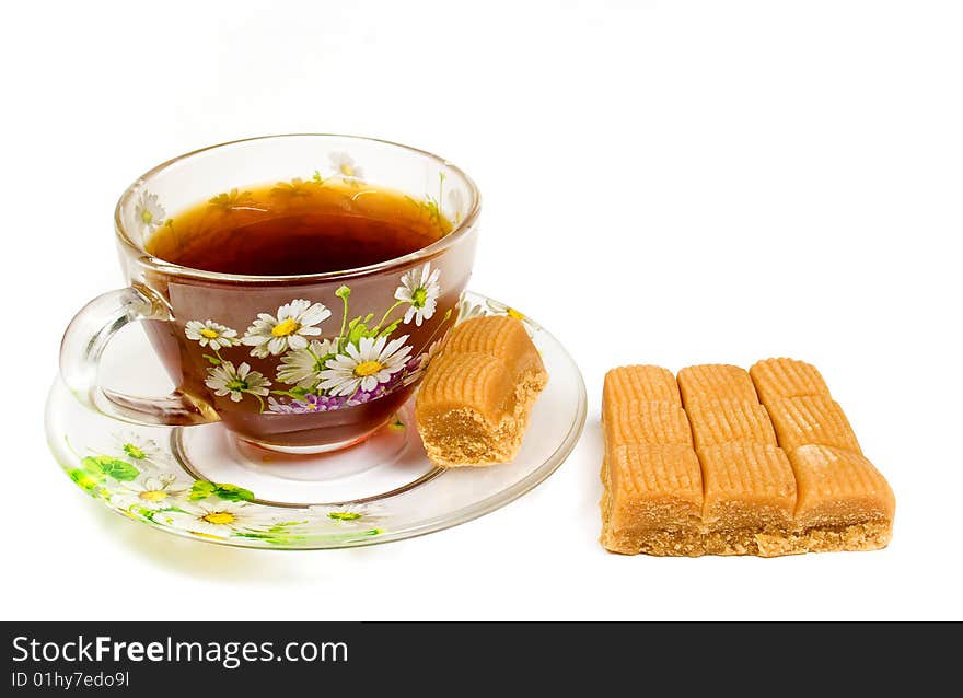 Cap of tea on saucer with toffee on white