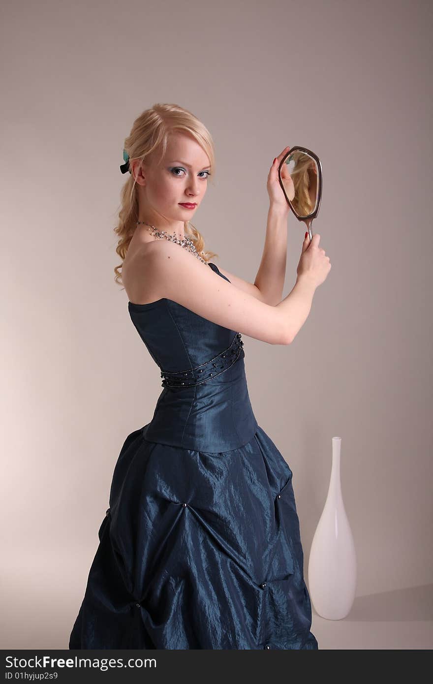 Beautiful young woman wearing a blue prom dress and silver mirror. Beautiful young woman wearing a blue prom dress and silver mirror