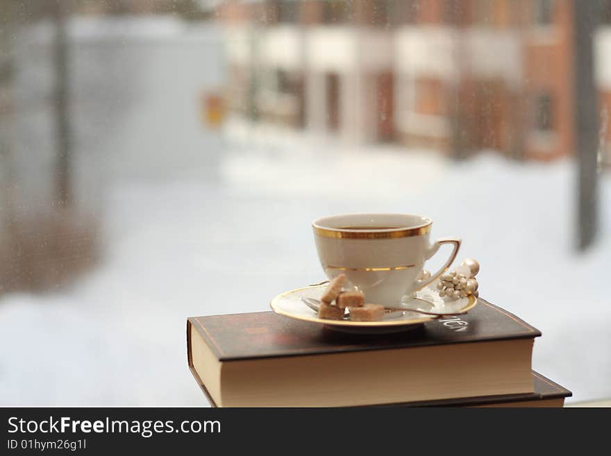 Porcelain cup with coffee on a stack of books by the window. Porcelain cup with coffee on a stack of books by the window