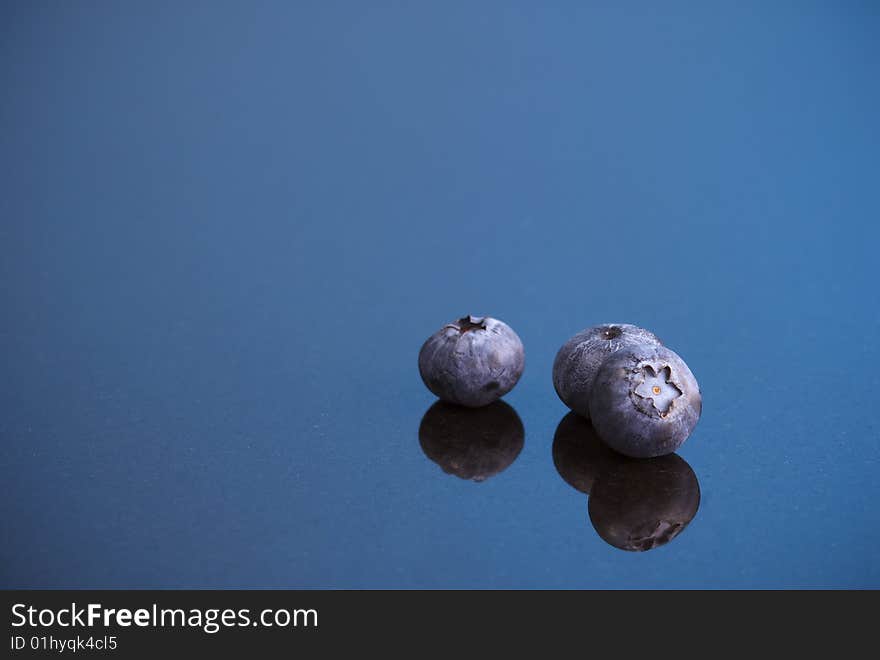 Blueberries reflected in marble against a blue background. Blueberries reflected in marble against a blue background.