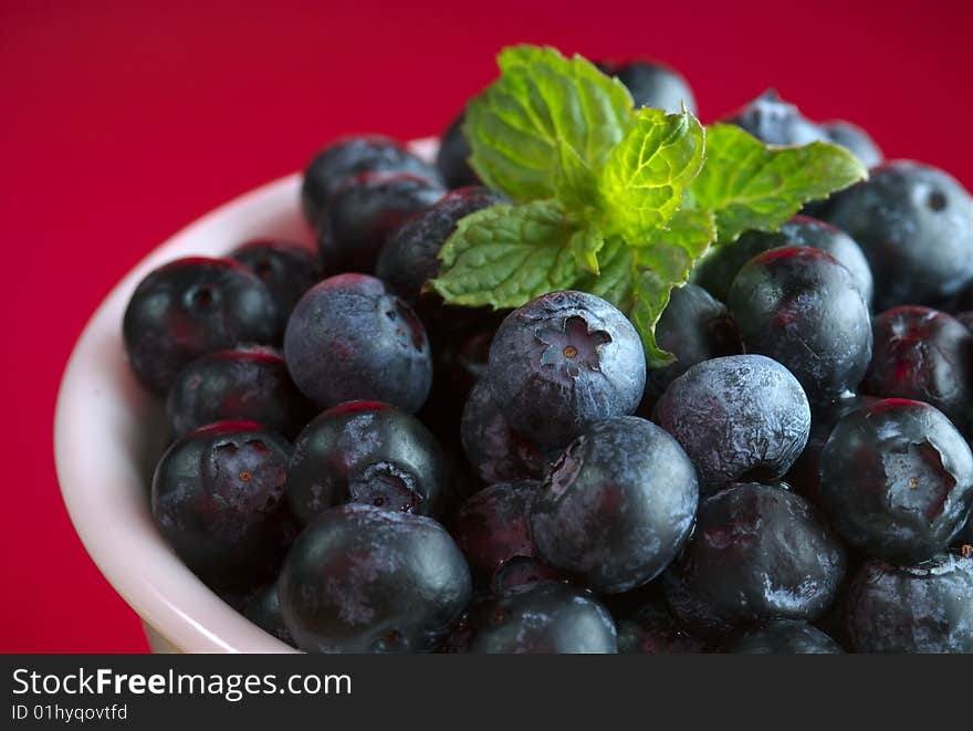 Blueberries in bowl on red background