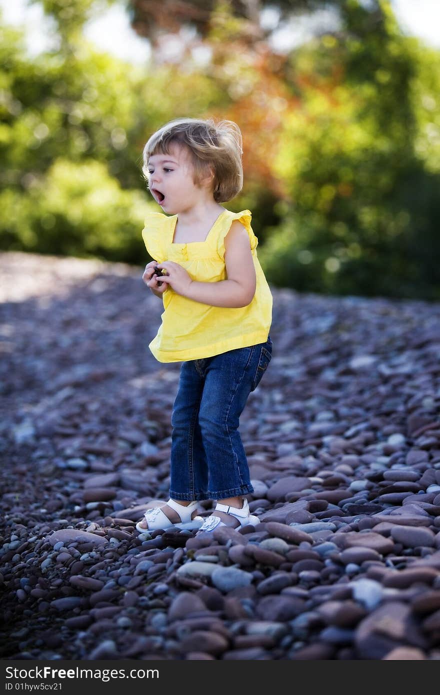 A preschooler happily tossing rocks into a lake.