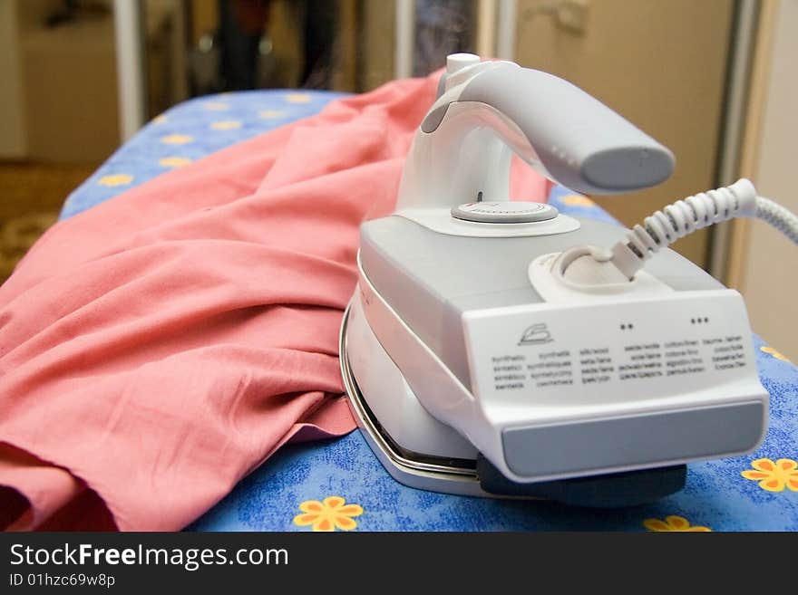 On an ironing table an iron and a shirt