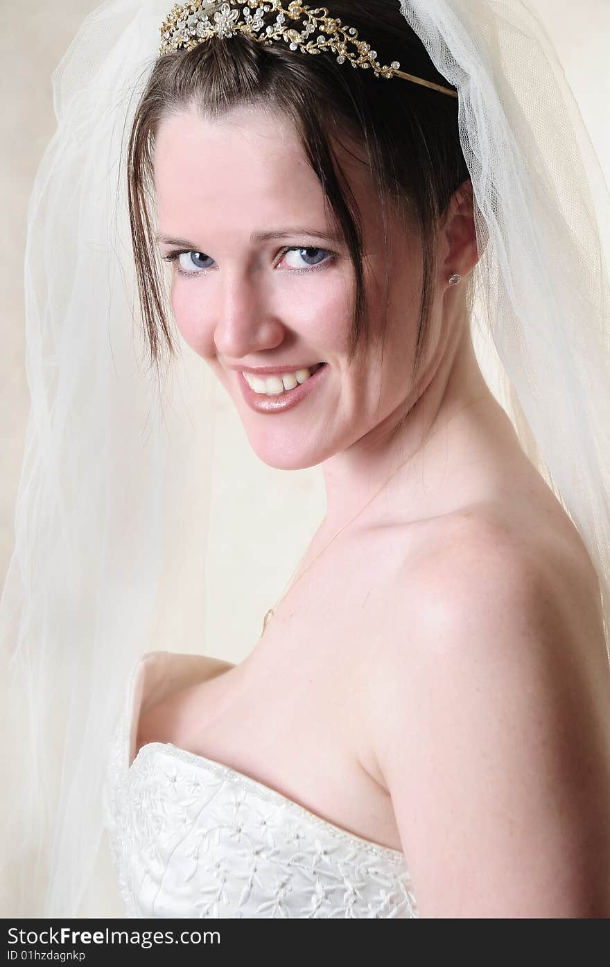 Female model standing in her wedding dress in a studio smiling at the camera. Female model standing in her wedding dress in a studio smiling at the camera