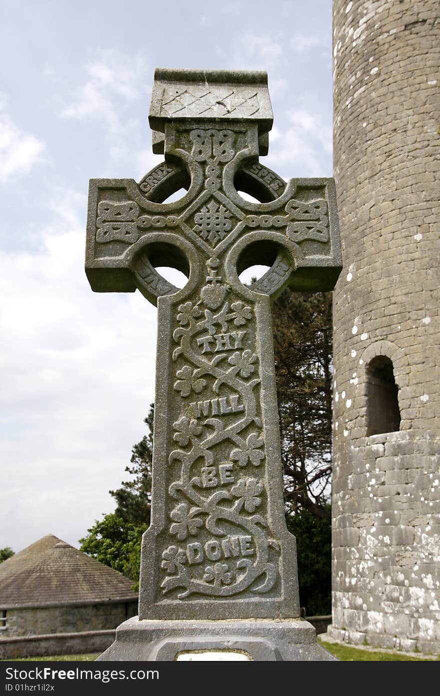 Old irish stone cross in front of a tower. Old irish stone cross in front of a tower