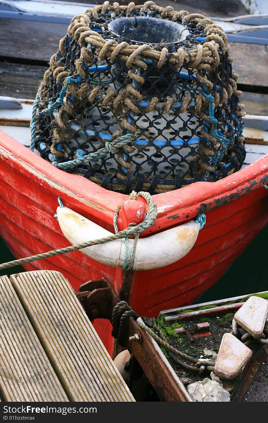 A Lobster and Crab pot at the front of a small red fishing boat located at Salcombe Bay, Devon England UK. A Lobster and Crab pot at the front of a small red fishing boat located at Salcombe Bay, Devon England UK.