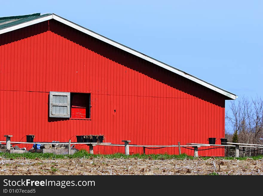 Broad side of a red barn with a window.