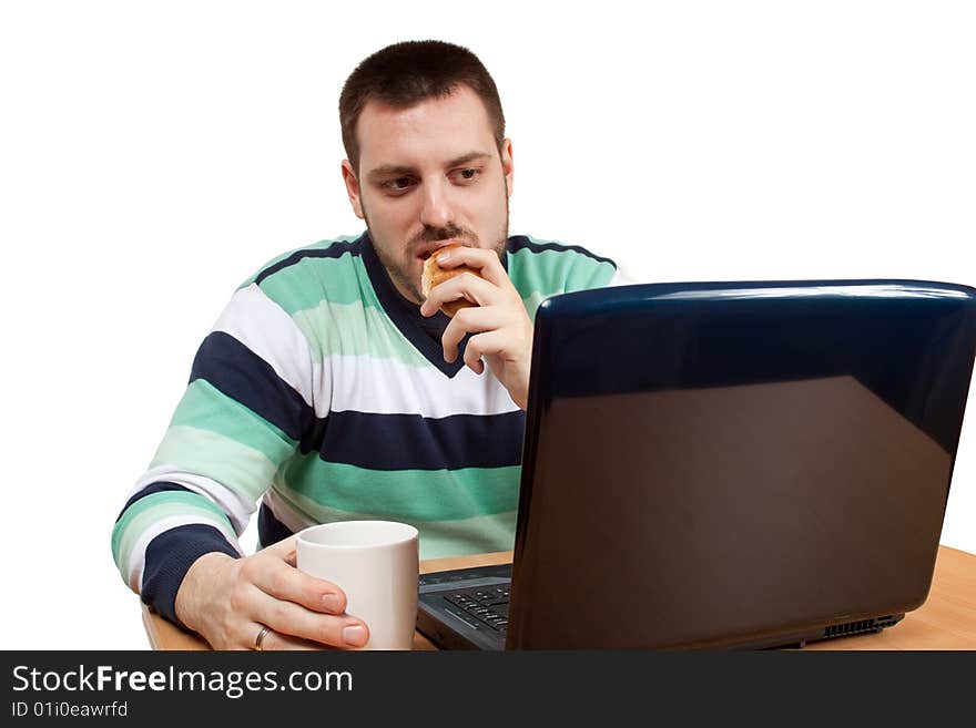 Man having his breakfast in front of his notebook. Man having his breakfast in front of his notebook